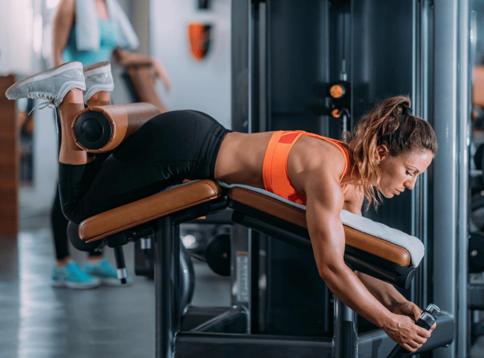 Glute-Ham Raise cvik na hamstringy cvičí žena vo fitku-alt