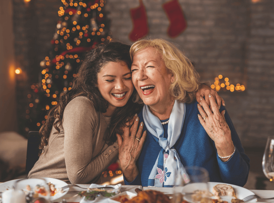 babička a vnučka se smějí u vánočního svátečního stolu s jídlem-cz-alt