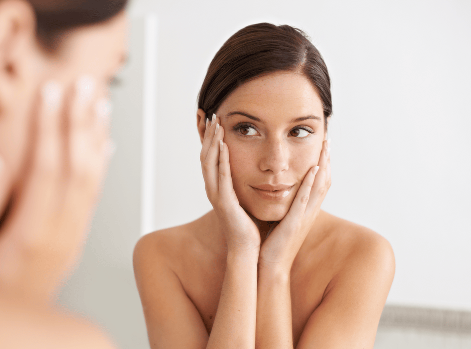 Kobieta przed lustrem podczas codziennego rytuału pielęgnacji dla promiennej i zdrowej skóry