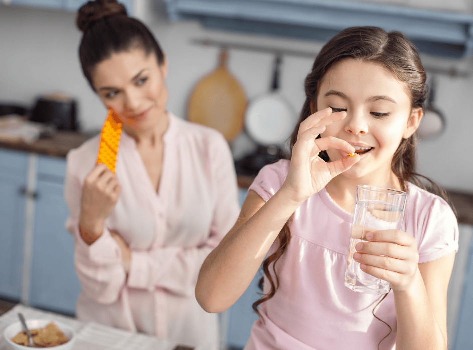 holčička užívá vitamíny za ní stojí matka-cz-alt