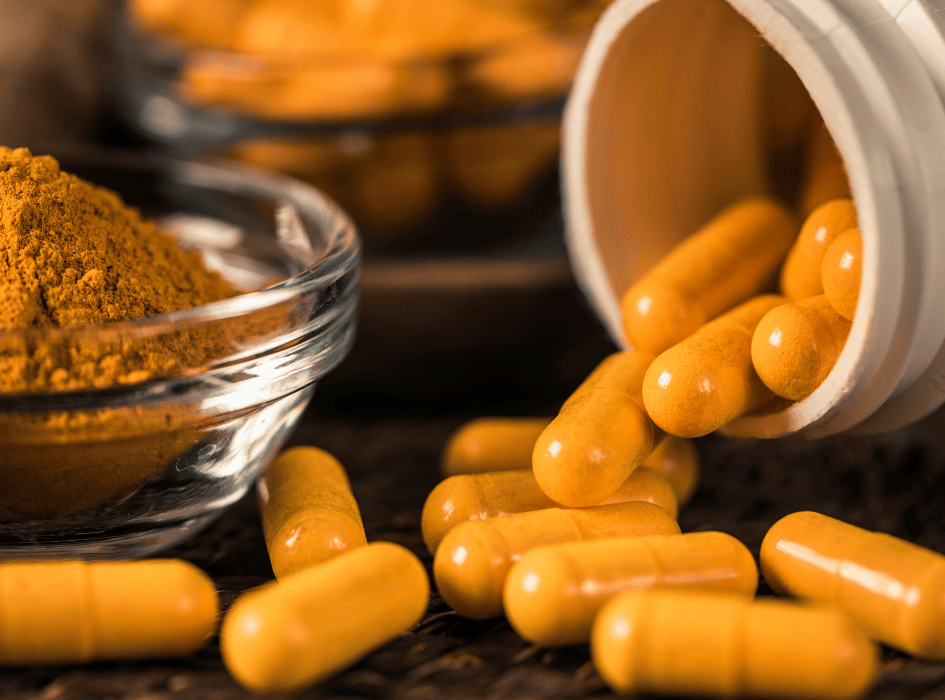 kurkuma v kapsuliach vysypané na stole-alt