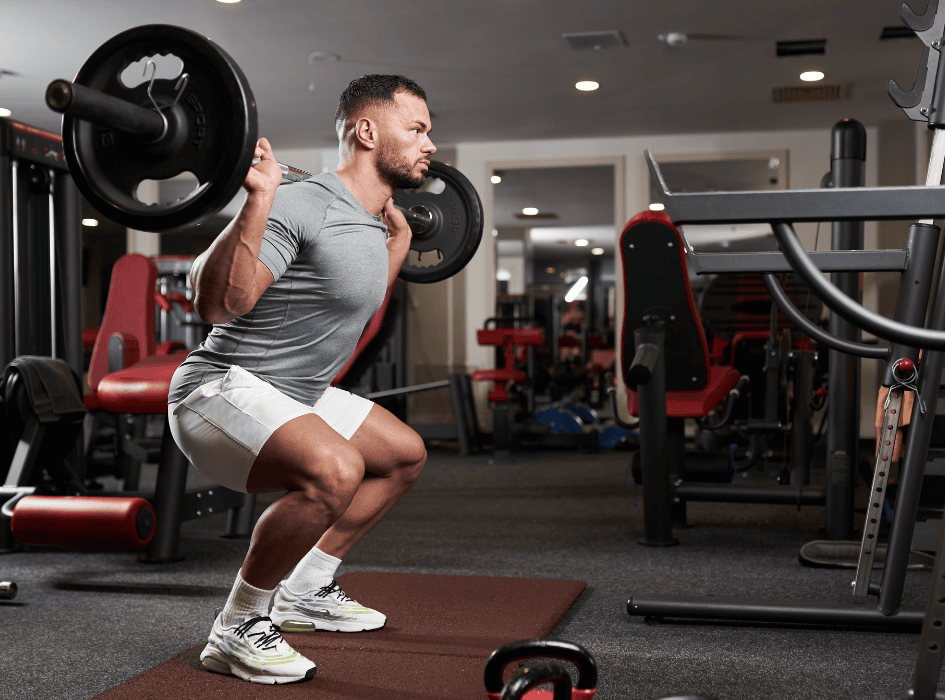 muž cvičí cvik na nohy, zadní dřep s velkou činkou-cz-alt