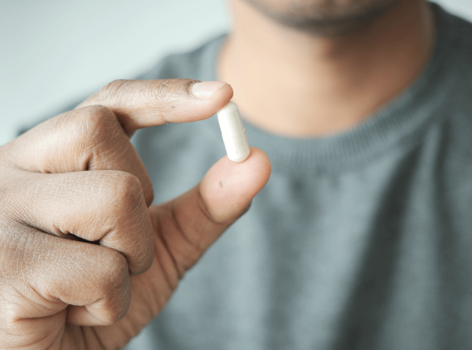 muž drží ve 2 prstech bílou kapsli-cz-alt