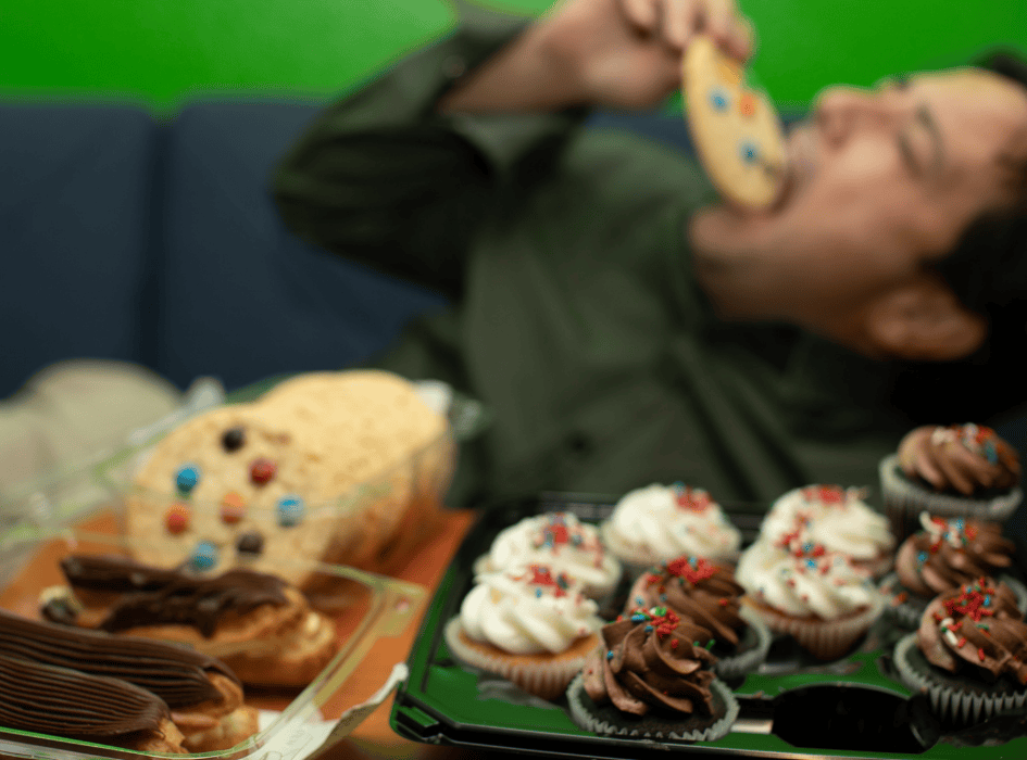 muž leží na gauči a přejídá se koláči a zákusky-cz-alt