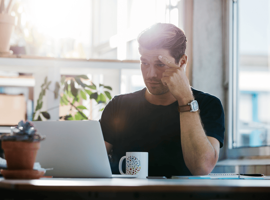muž sa sústredí pri počítači a má na stole kávu-alt