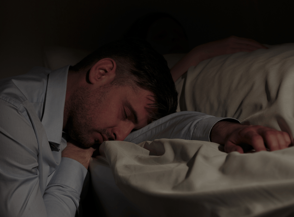 Mężczyzna zasnął ze zmęczenia na boku łóżka.