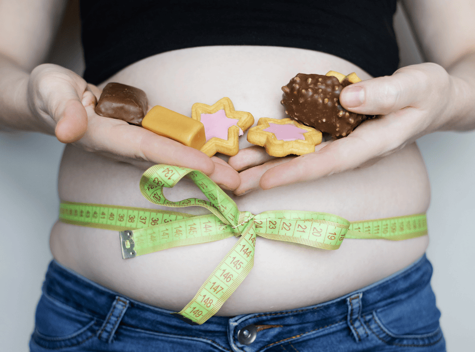žena má nafúknuté brucho a na ňom meter a zákusky-alt