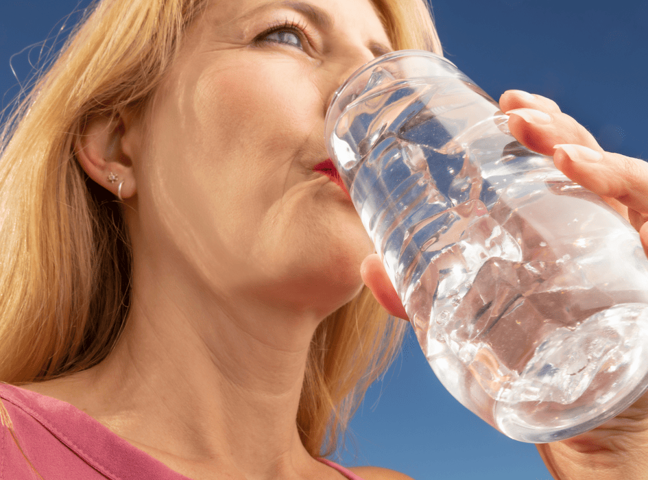 žena pije z pohára vodu