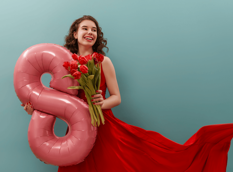 Žena sa usmieva a drží kvety, ktoré dostala k Medzinárodnému dňu žien