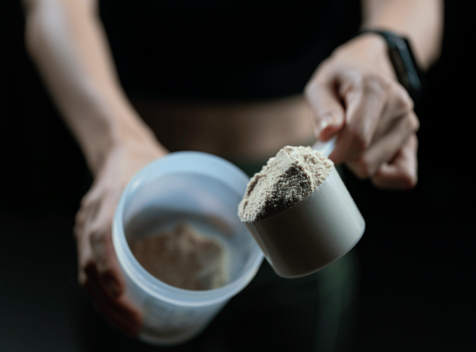 žena sype protein z odměrky do šejkru-cz-alt